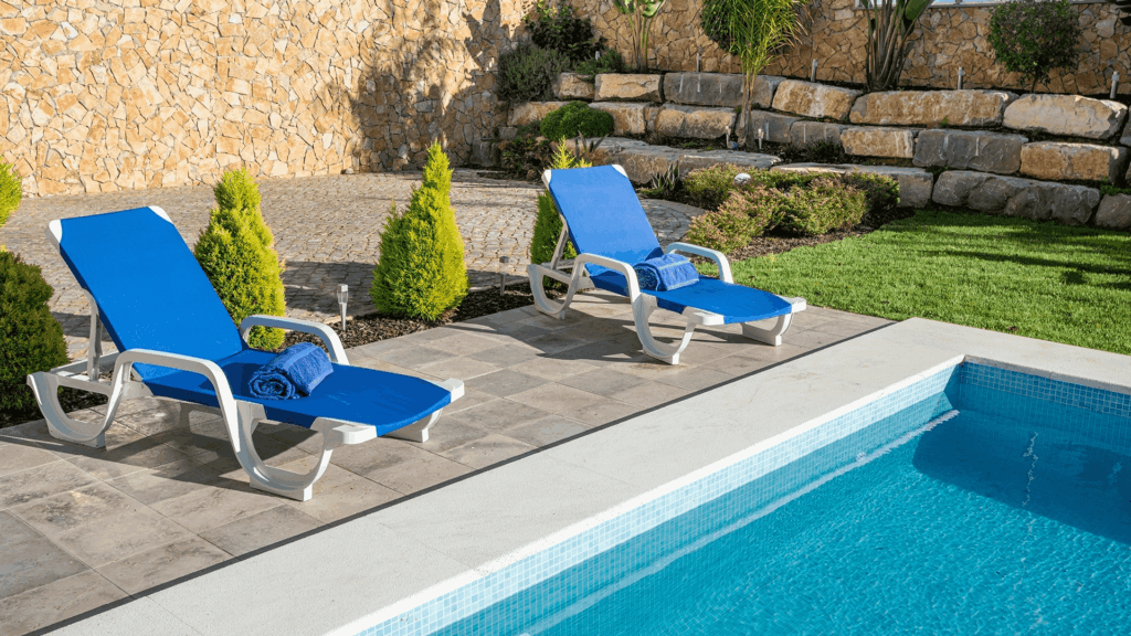 blue lounge chairs with folded blue towels on them next to a pool