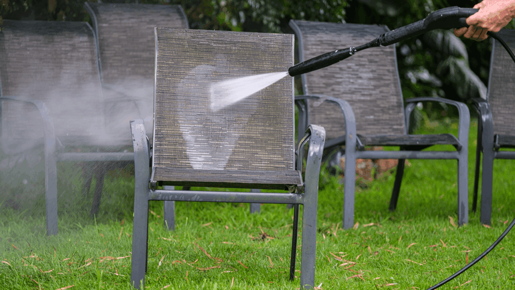 man water blasting a mesh sling chair next to similar chairs